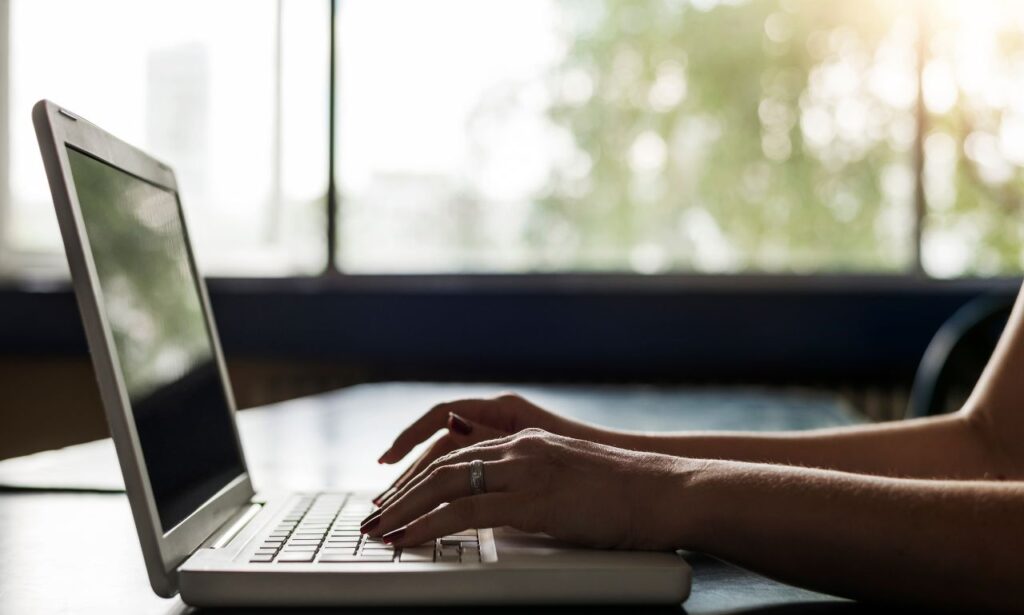 Woman's hands typing on a laptop