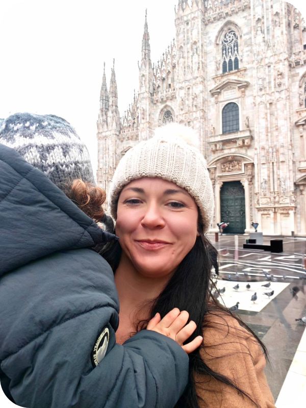 Woman holding child in front of Milan Duomo.