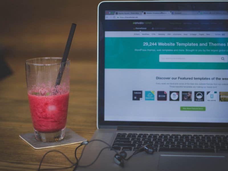 macbook opened to a website builder with smoothie next to it for a post on where to sell digital products