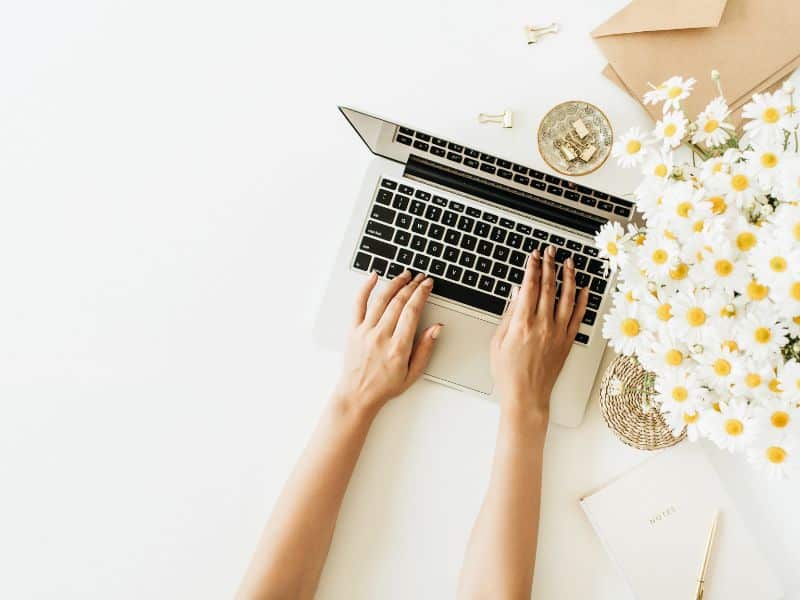 womans hands on macbook with daisies figuring out meta ads best practices