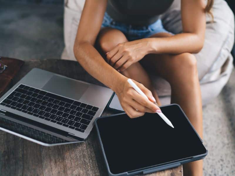 faceless woman sitting with two laptops open