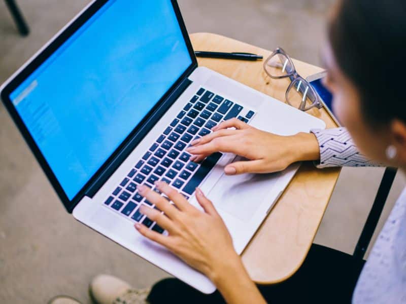 Faceless woman writing a sales page for a digital product.