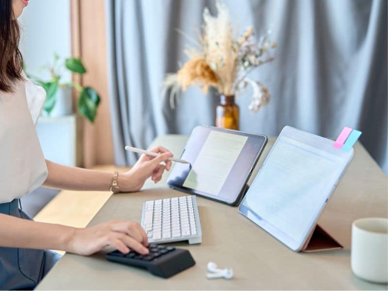 faceless woman doing work at a laptop on a standing desk.